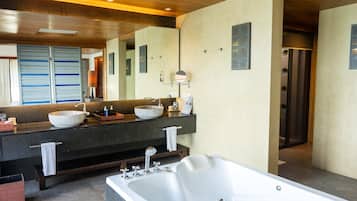 A modern bathroom with a large bathtub, two sinks with vessel basins, and a large mirror.
