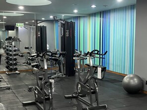 Un gimnasio con varios equipos de ejercicio, incluyendo cintas de correr y máquinas de pesas, y una pelota de ejercicios grande.