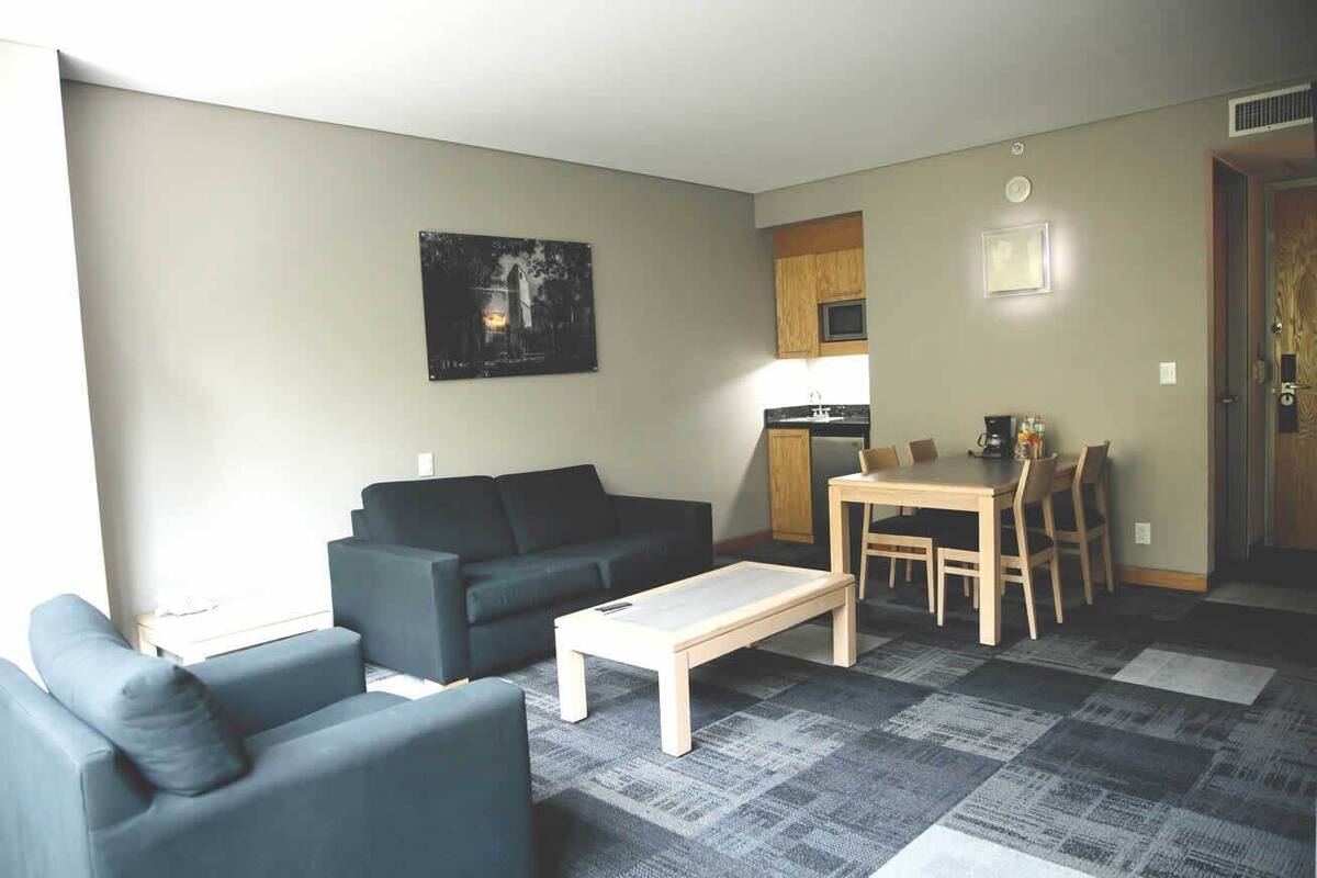 A living room with a sofa, a coffee table, and a dining area with a table and chairs.
