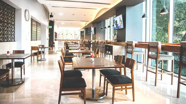 A spacious restaurant with high ceilings, modern furniture, and large windows offering a view of the outdoors. - Holiday Inn Express Mexico Reforma by IHG (Mexico City)