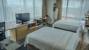 A hotel room with two beds, a desk with a TV, and a view of the city through large windows. - Holiday Inn Express Mexico Reforma by IHG (Mexico City)
