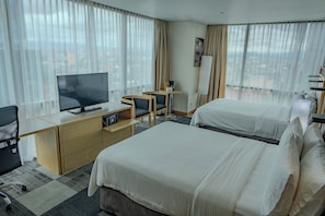 A hotel room with two beds, a desk with a TV, and a view of the city through large windows. - Holiday Inn Express Mexico Reforma by IHG (Mexico City)
