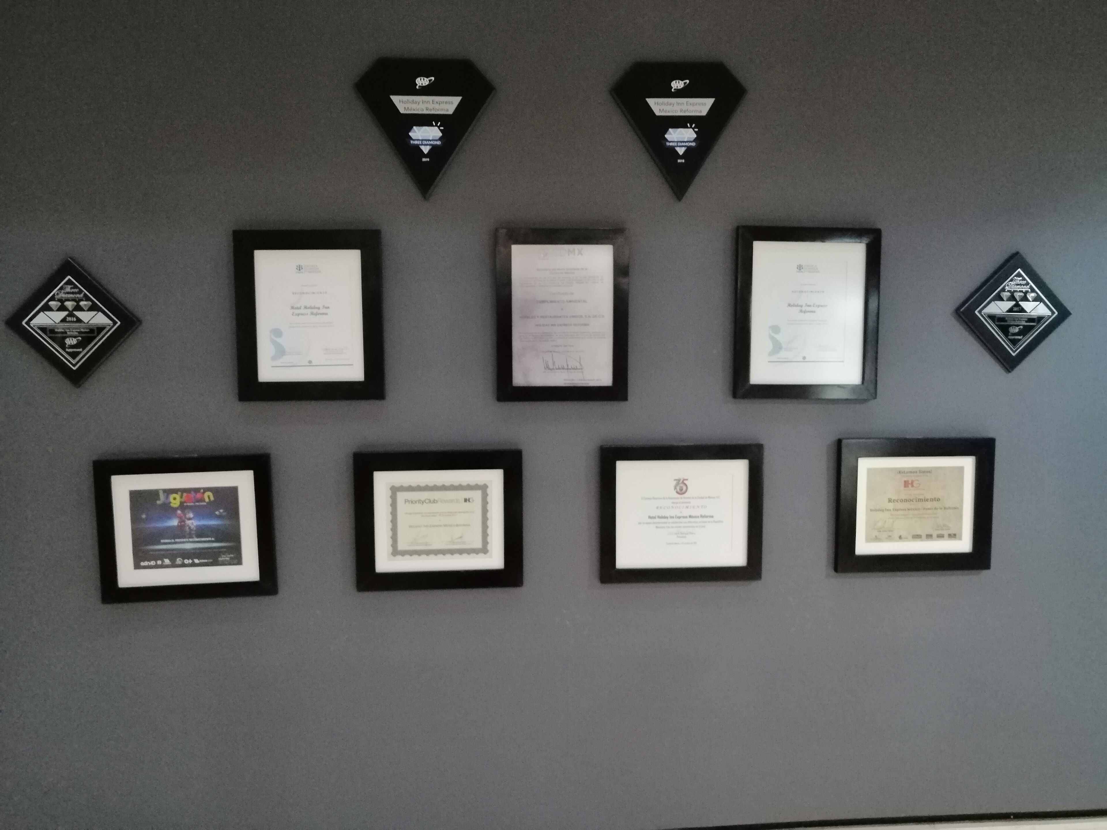 A wall displaying various framed awards and certificates.