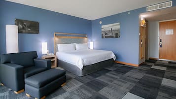 A hotel room with a bed, a desk, a chair, and a door.