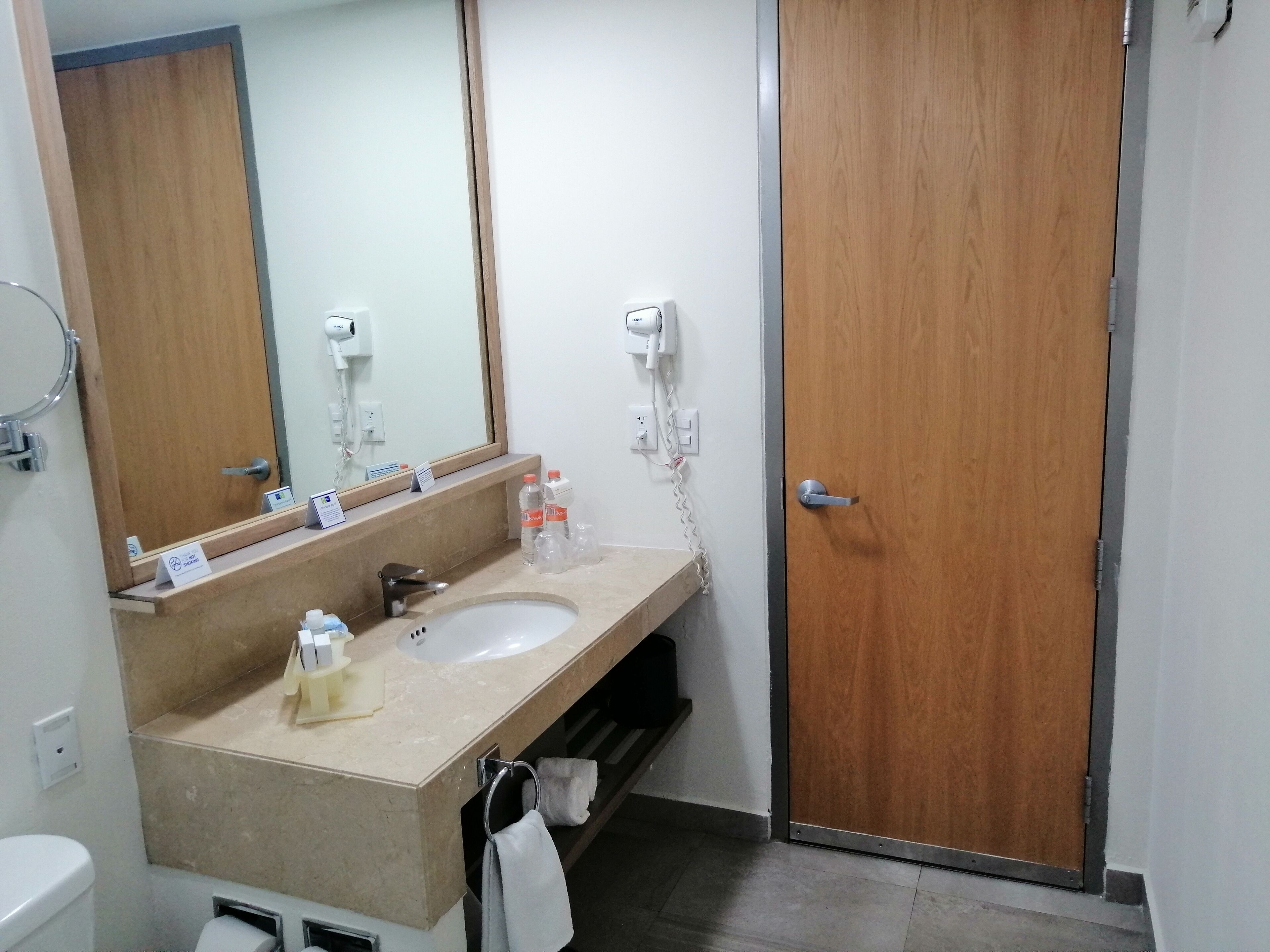 A bathroom with a sink, mirror, hairdryer, and towel rack.