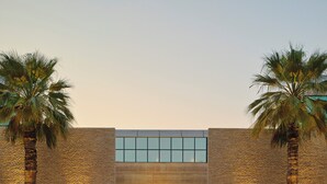 A modern building with a large glass window and a statue in front.