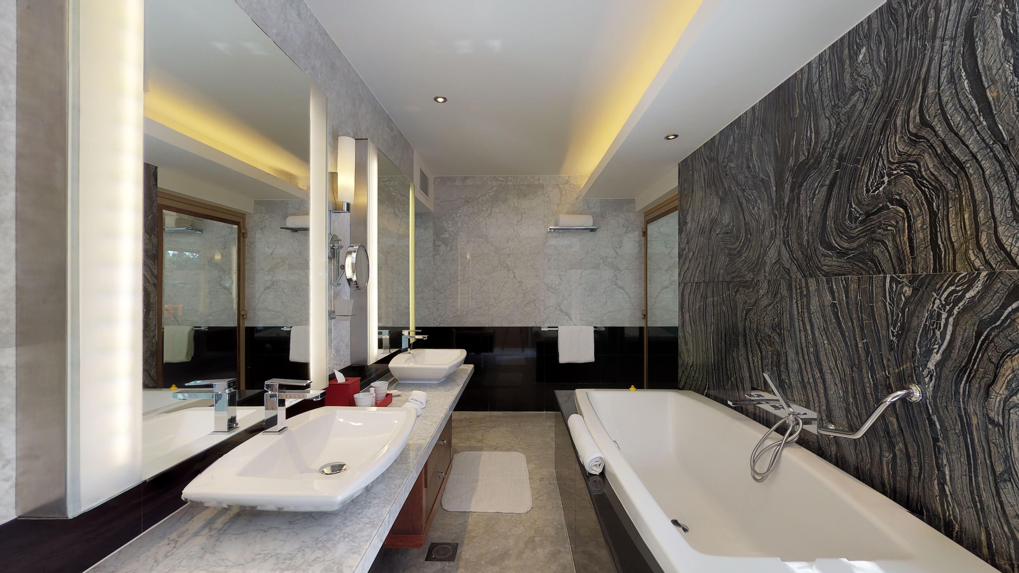 A modern bathroom with two sinks, a bathtub, and a large mirror.