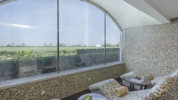 A room with a large window, patterned walls, and a seating area with a table.