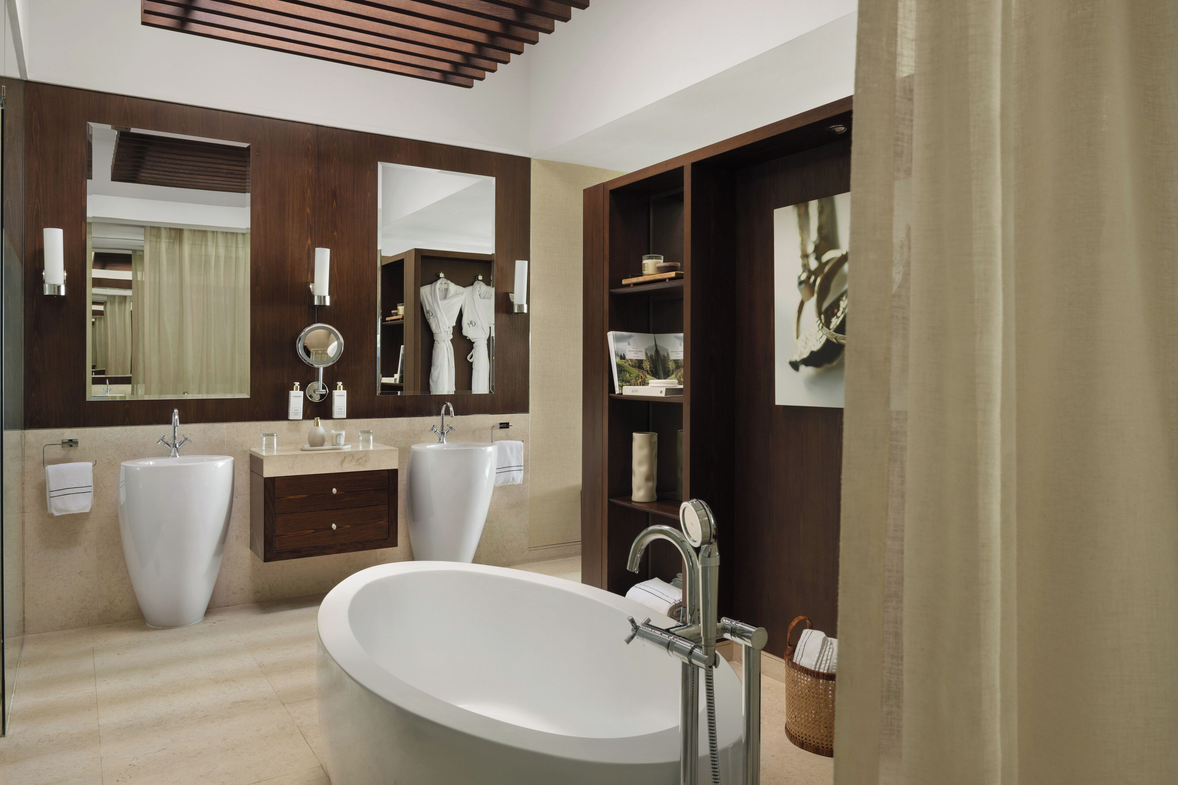 A modern bathroom with a freestanding bathtub, two sinks, and a large mirror.