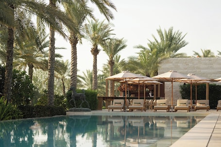 Una piscina al aire libre, sombrillas, sillones reclinables de piscina