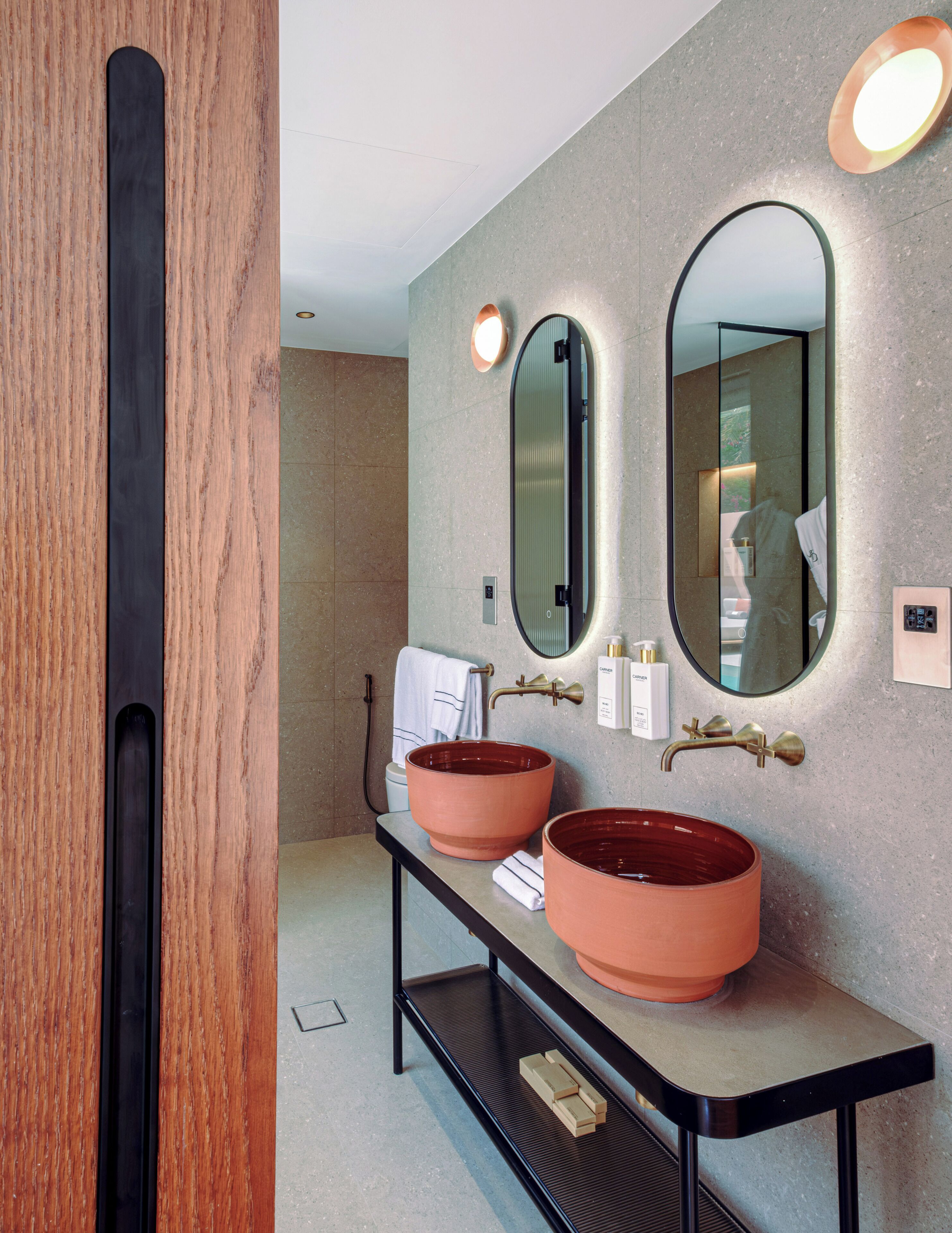 A modern bathroom with two large, oval-shaped sinks, a mirror, and a towel rack.