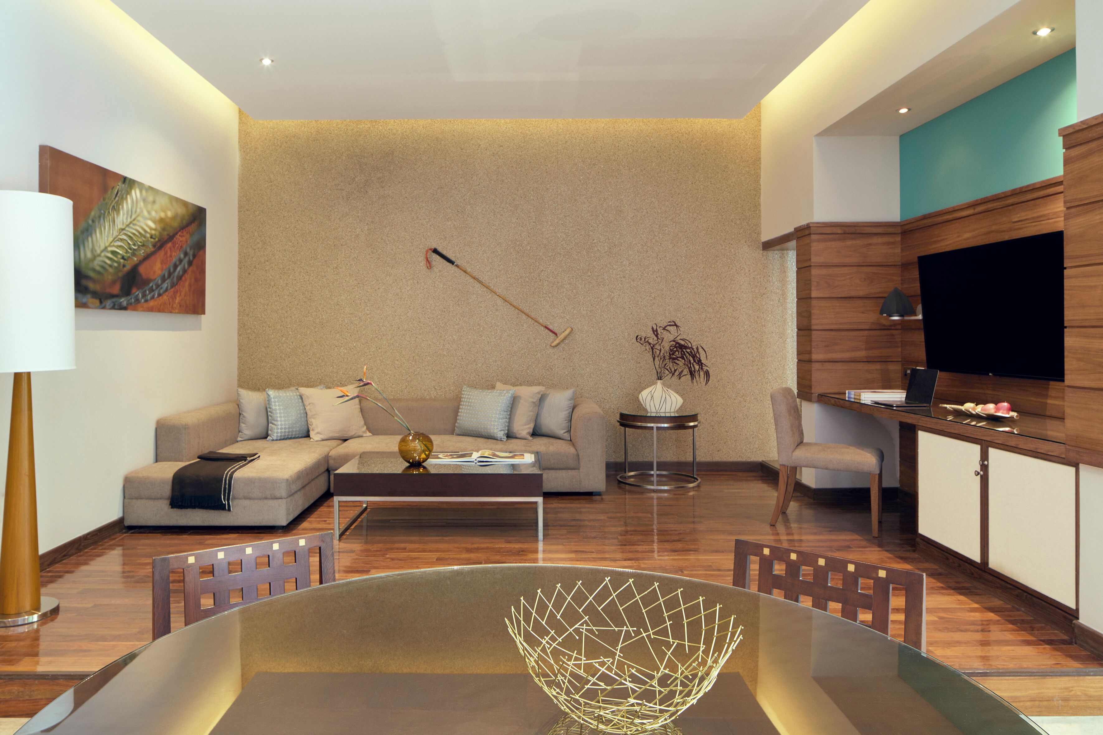 Una sala moderna con un sofá seccional, una mesa de comedor con sillas, un televisor y un jarrón decorativo.