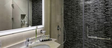 Une salle de bain moderne avec un grand miroir, un lavabo et une douche à parois de verre.