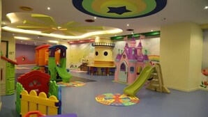 Un espace de jeux pour enfants avec des structures colorées et une fresque représentant un château sur le mur.