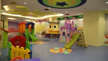 Children can play and climb in this enclosed play area featuring slides, climbing frames, and a castle-themed playhouse.