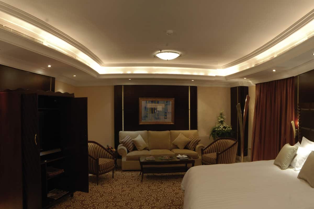Habitación de hotel con cama, sofá, mesita de centro, televisión y armario.