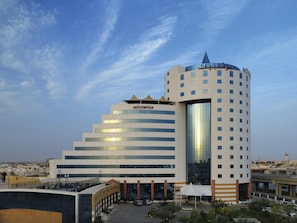A multi-story hotel with a prominent 'MÖVENPICK' sign, a rooftop terrace, and a parking area.