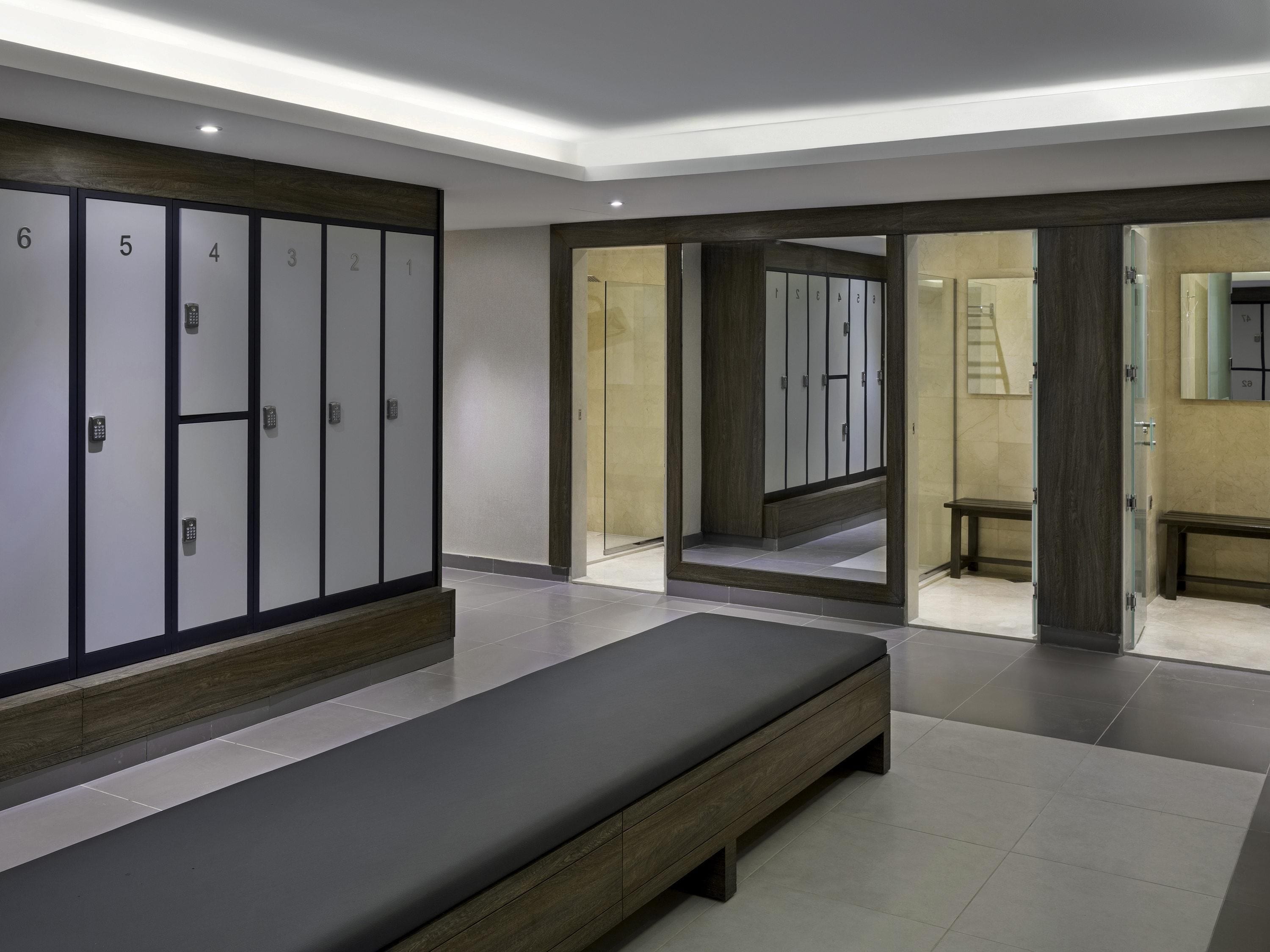 A modern hotel room with a large bed, a wardrobe with numbered doors, and a bathroom visible through an open door.