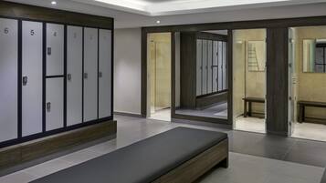 A modern hotel room with a large bed, a wardrobe with numbered doors, and a bathroom visible through an open door.