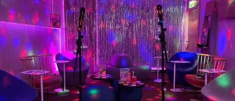 A room with a mirrored wall, two microphones, and a small table with a drink and a box.