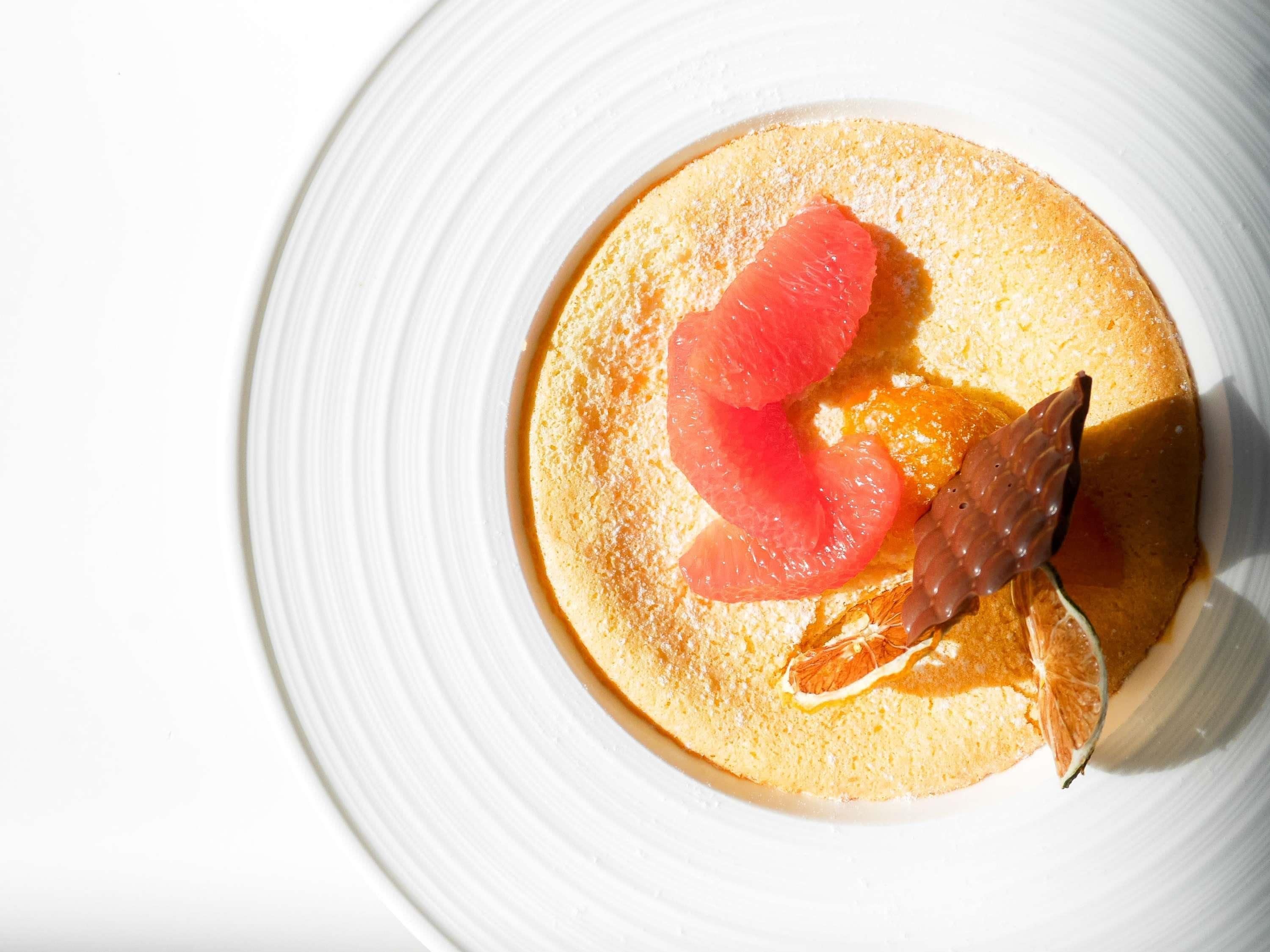 A dessert on a white plate with a citrus garnish.