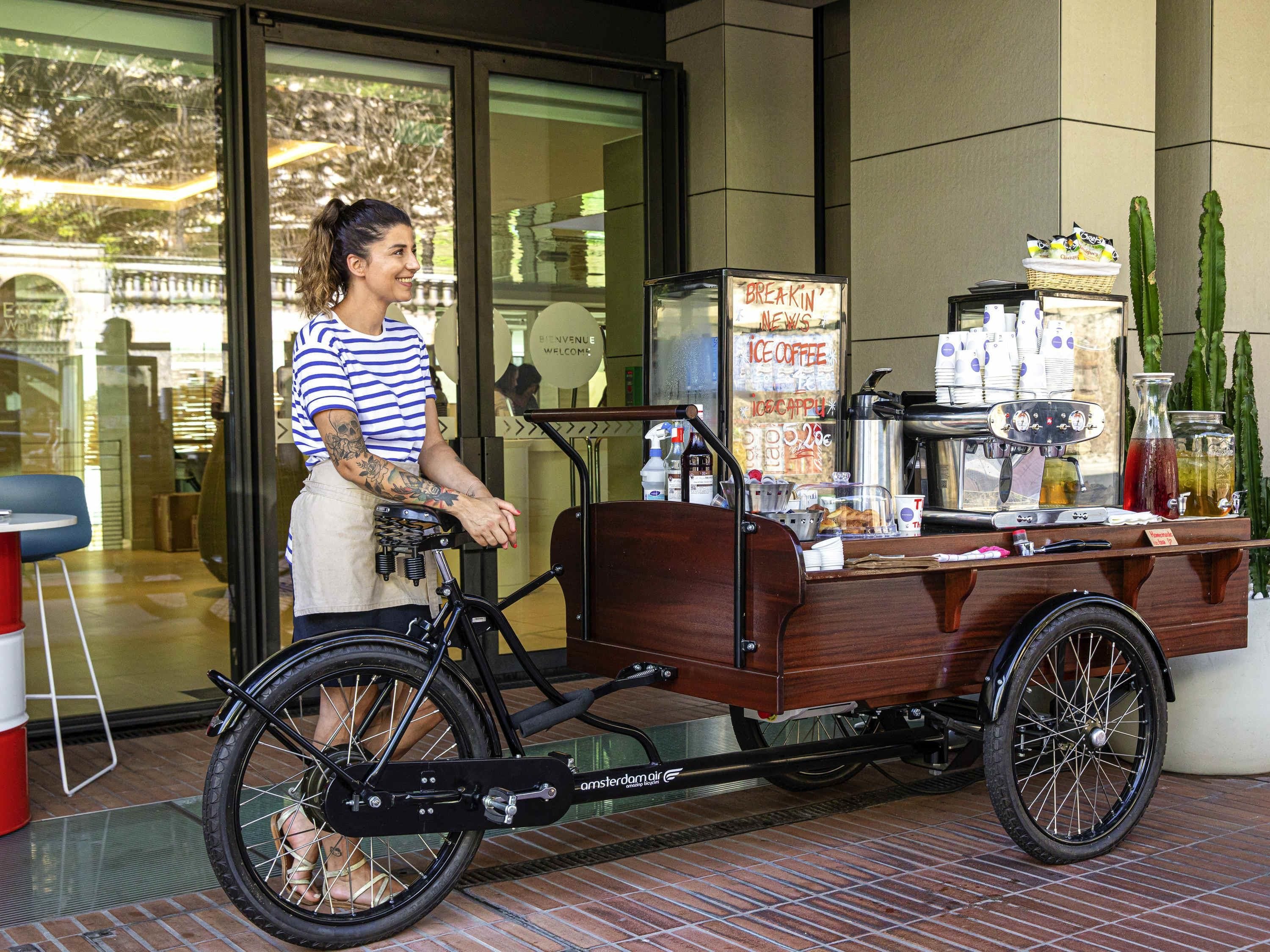 Un carrito de bicicleta con una máquina de café y un letrero que dice 'BREAKIN' NEWS ICE COFFEE'.