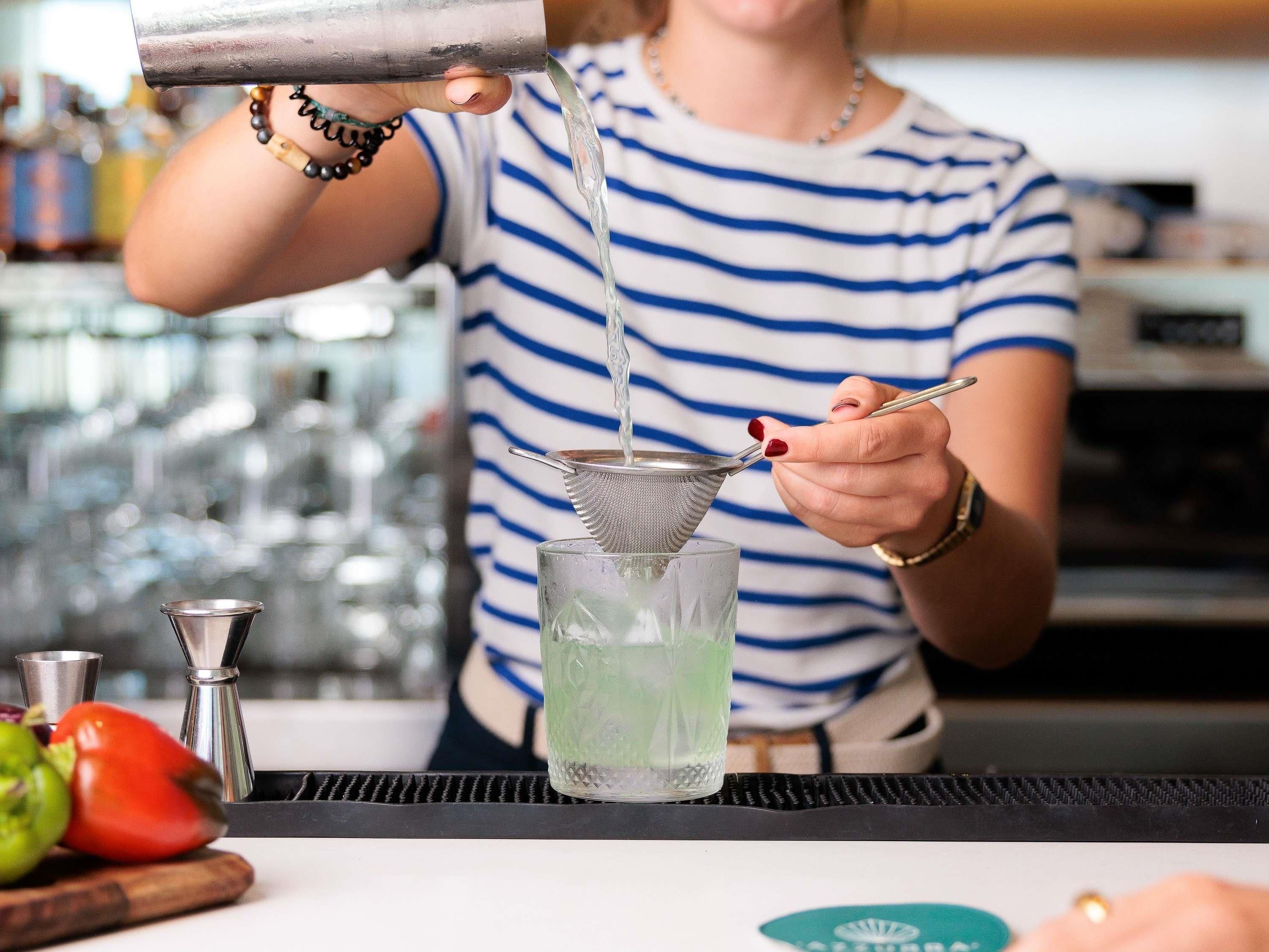 A bartender pouring a drink into a glass.