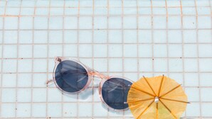 A tiled surface with a pair of sunglasses and a yellow umbrella.