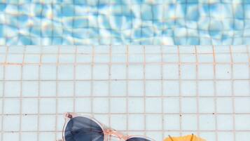 A tiled surface with a pair of sunglasses and a yellow umbrella.
