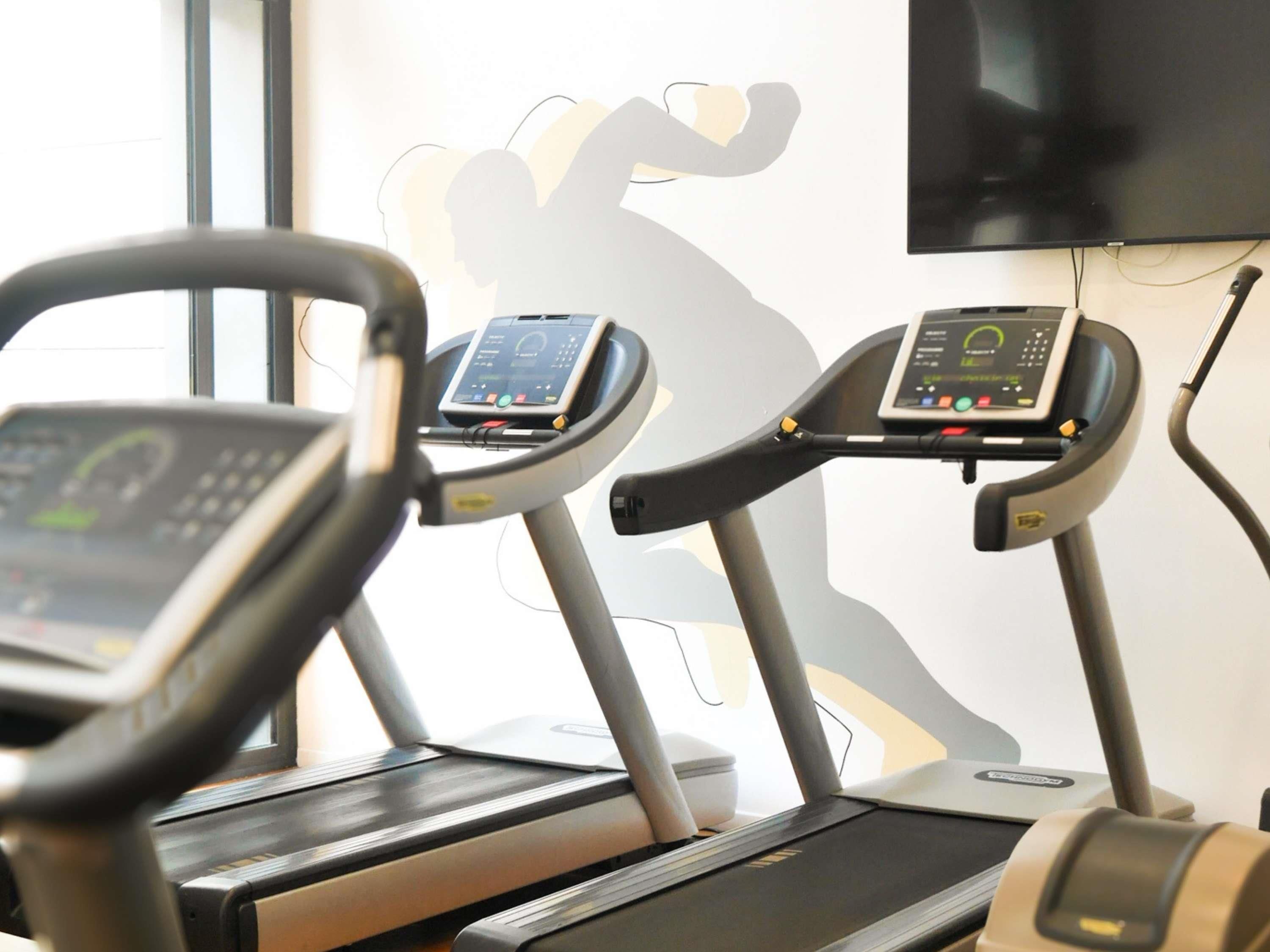 Un gimnasio con cintas de correr y una decoración en la pared.