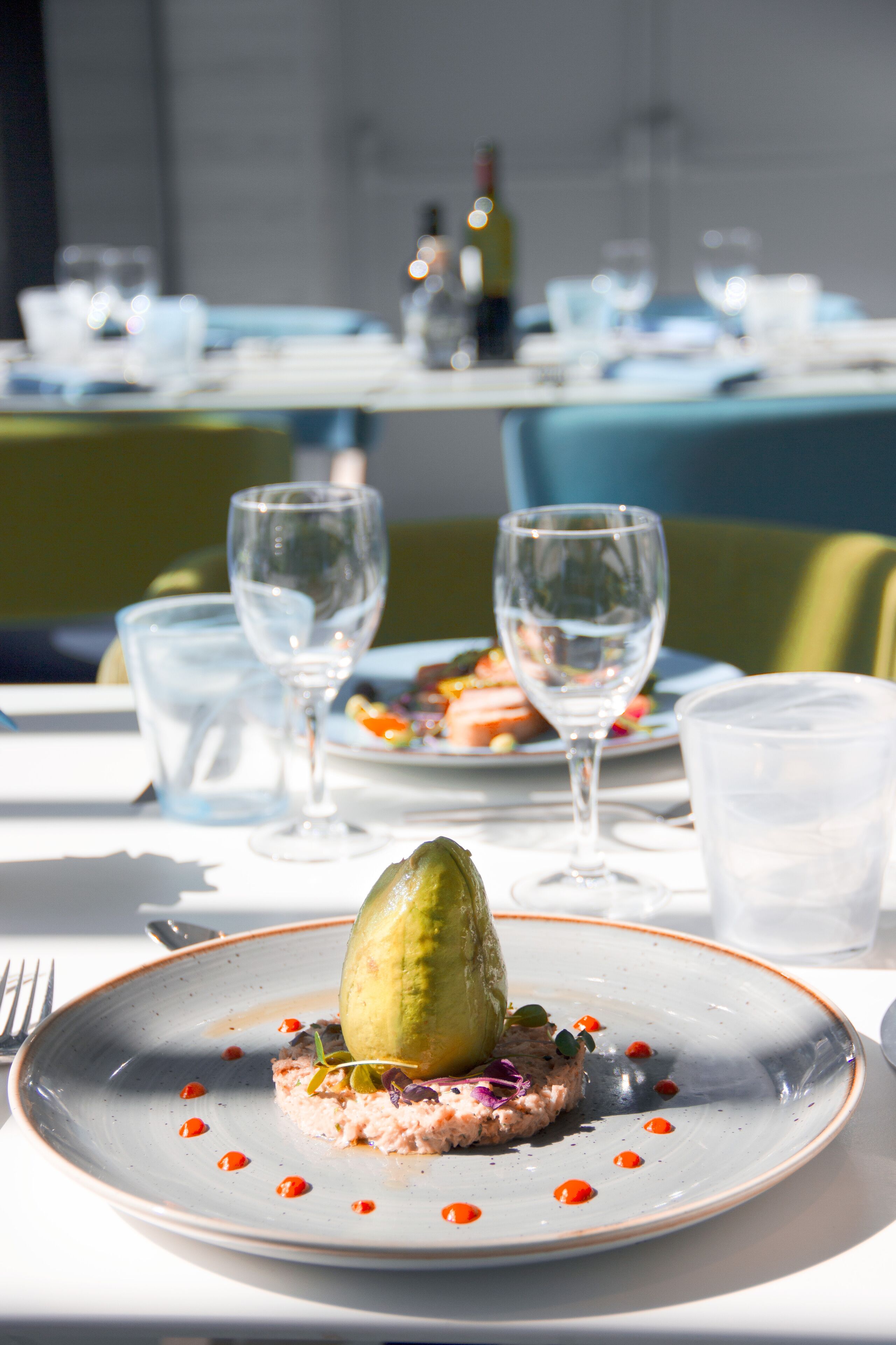 A dining table with plates of food, glasses, and a bottle.