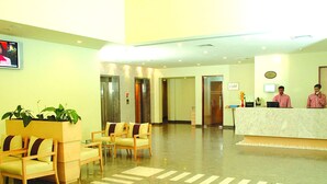 Un vestíbulo de hotel con mostrador de recepción, zona de estar y ascensores.
