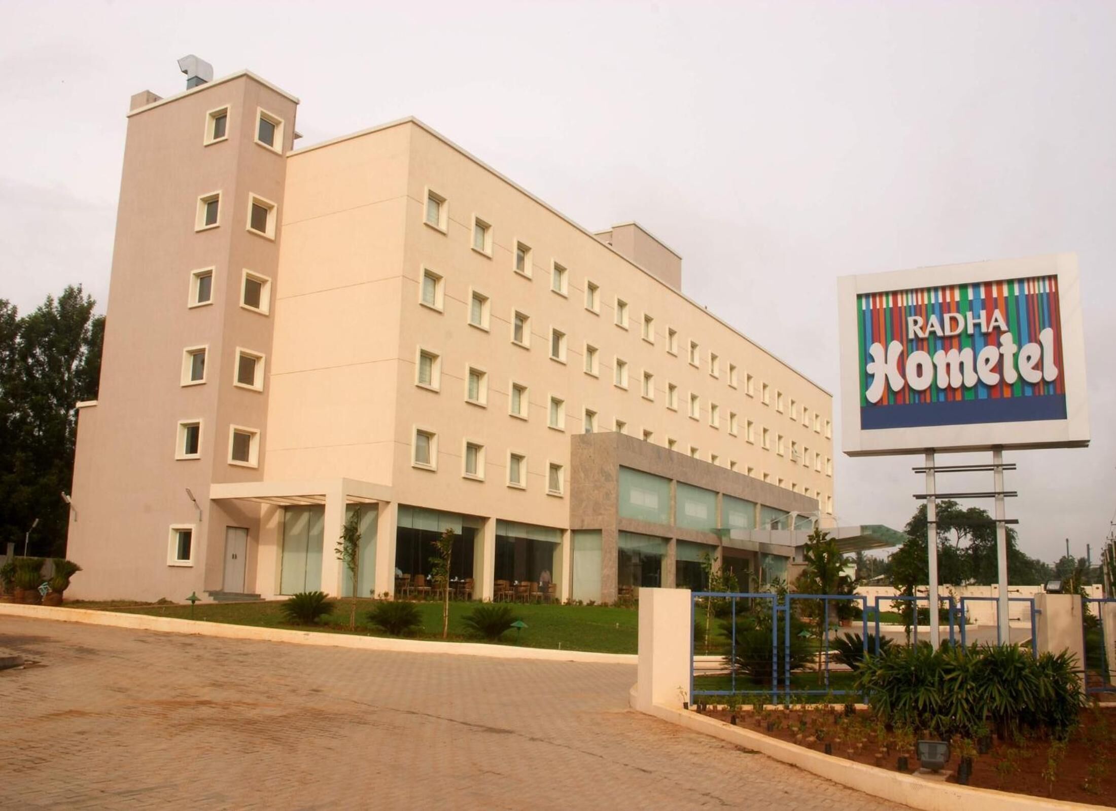 Un hôtel à plusieurs étages, doté d’une façade sobre, de grandes fenêtres et d’une enseigne indiquant « Radha Kometel ».