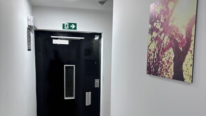 A hallway with a black door, a fire alarm, and a ceiling light. - Hotel Albert (Brussels)