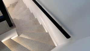 A staircase with a white wall and black handrail, leading to an upper floor. - Hotel Albert (Brussels)