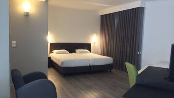 Habitación de hotel con una cama, dos lámparas de noche, un escritorio con silla y un televisor.