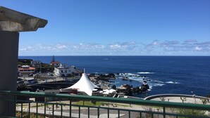 A coastal view with a white building and a white tent-like structure near the water. - Hotel Euro Moniz (Porto Moniz)