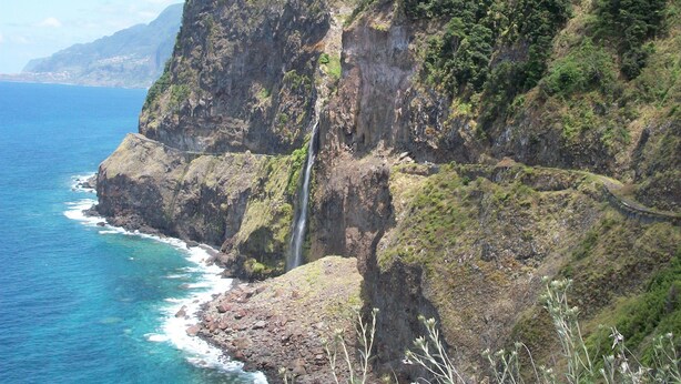 A coastal landscape with a waterfall, rocky cliffs, and clear blue sea. - Hotel Euro Moniz (Porto Moniz)