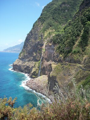 A coastal landscape with a waterfall, rocky cliffs, and clear blue sea. - Hotel Euro Moniz (Porto Moniz)