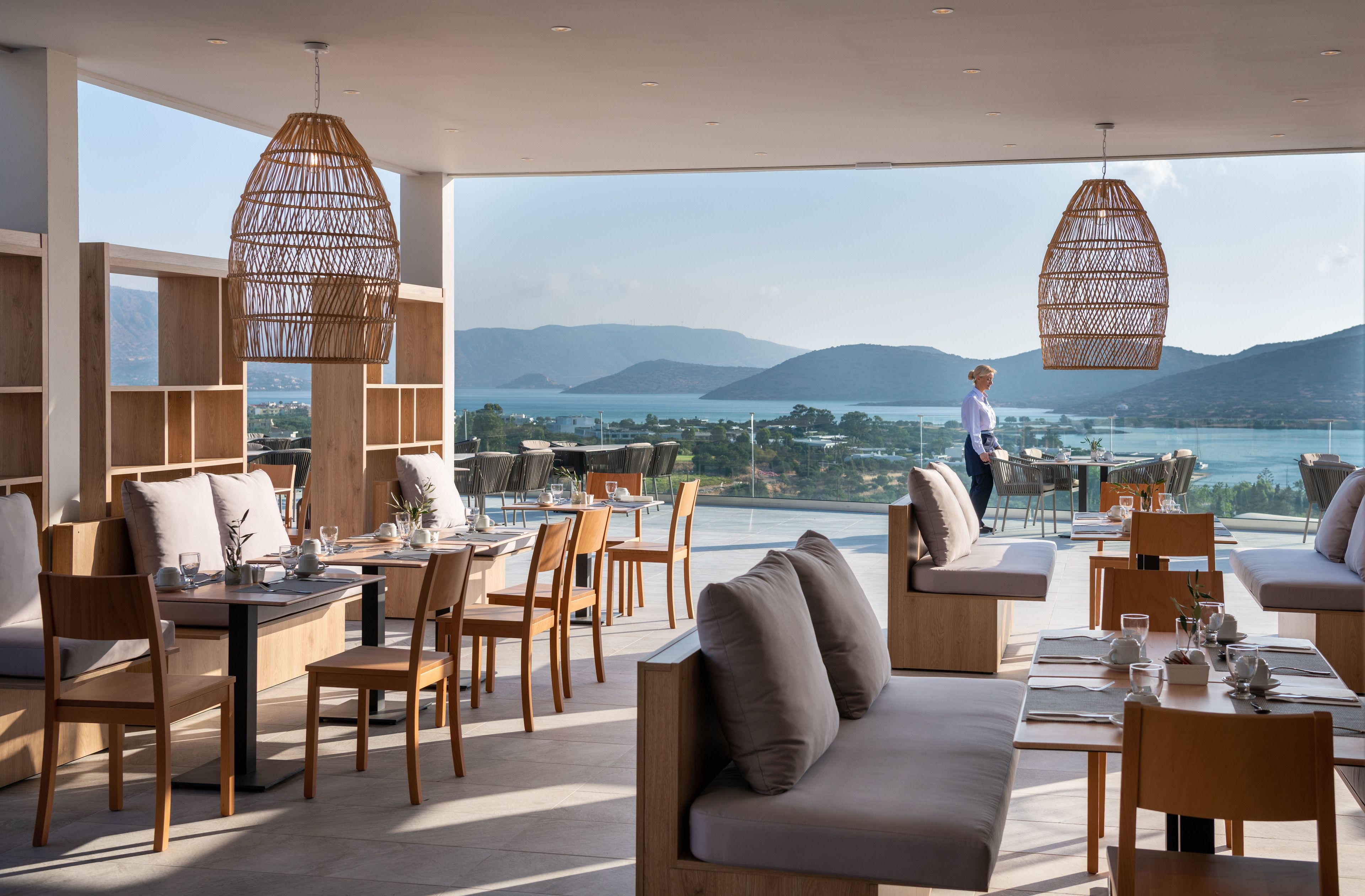 A spacious outdoor dining area with wooden furniture and a view of the sea.