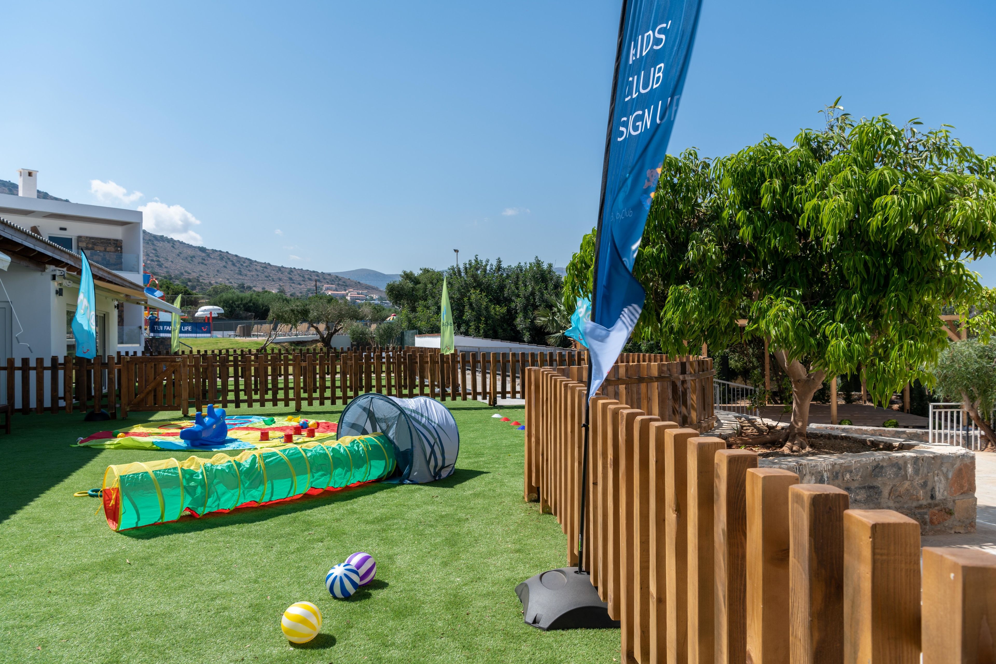 Un espace de jeux extérieur clôturé, comprenant une tente, une piscine gonflable et divers jouets.