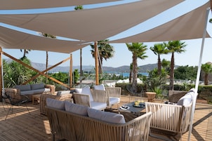 A covered outdoor seating area with wicker furniture and a view of the mountains.