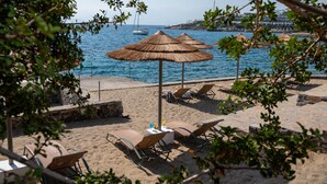 Un cadre idyllique au bord de la plage, avec des parasols en chaume, des chaises longues et une vue sur la mer.