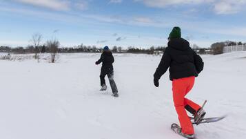 Dos personas hacen snowboard sobre una superficie nevada y plana, con cielo despejado al fondo.