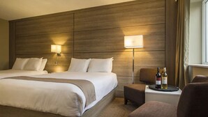 A hotel room with a large bed, two bedside lamps, a small table with a bottle, and a chair. - Living Stone Golf Resort (Collingwood)