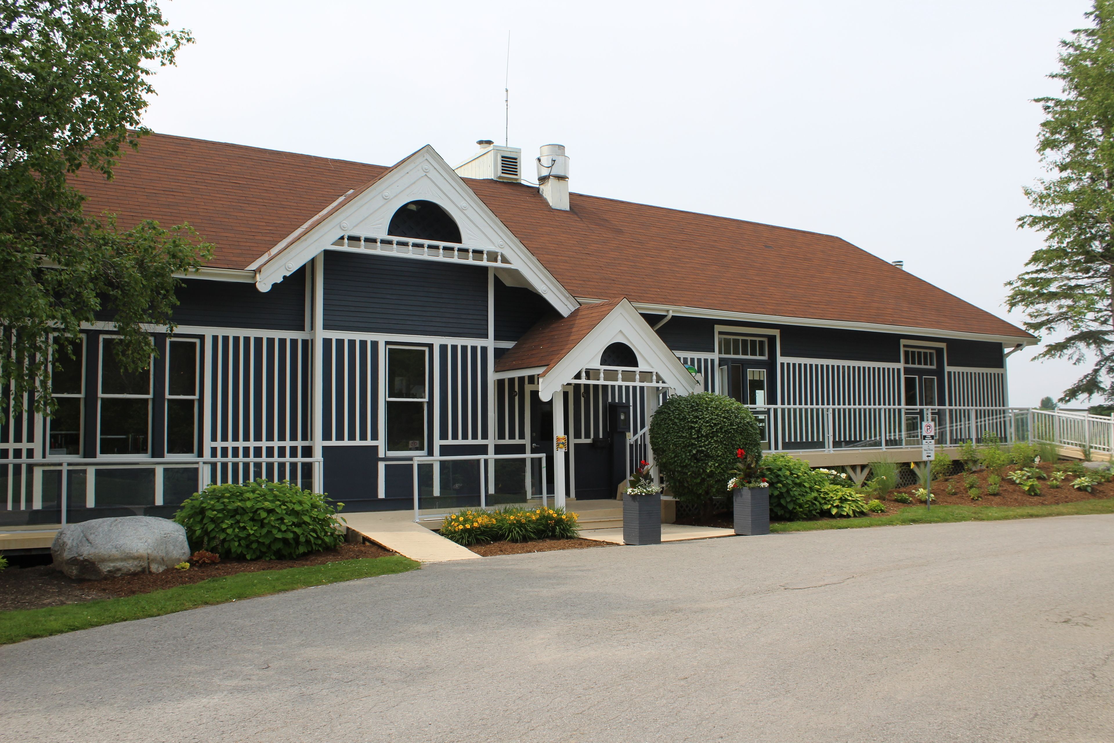 A two-story building with a dark facade, white trim, and a red-tiled roof.