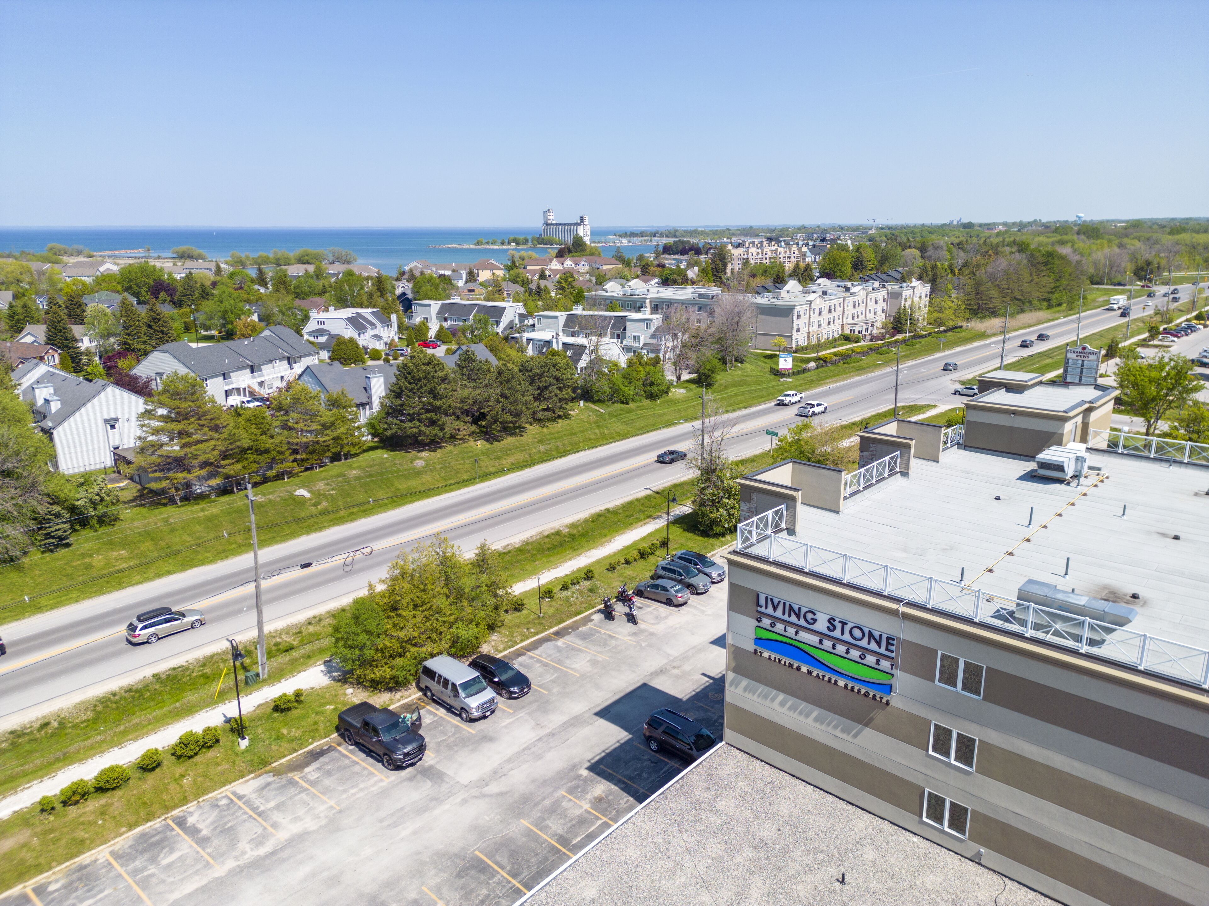 A golf resort with a parking lot, a road with vehicles, and a view of the ocean.