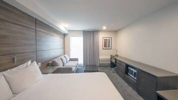 Une chambre d’hôtel moderne équipée d’un grand lit, d’un canapé, d’un bureau et d’un four encastré.