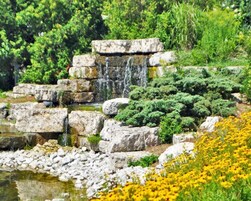 Un paisaje natural con una cascada en cascada, terreno rocoso y abundante vegetación.