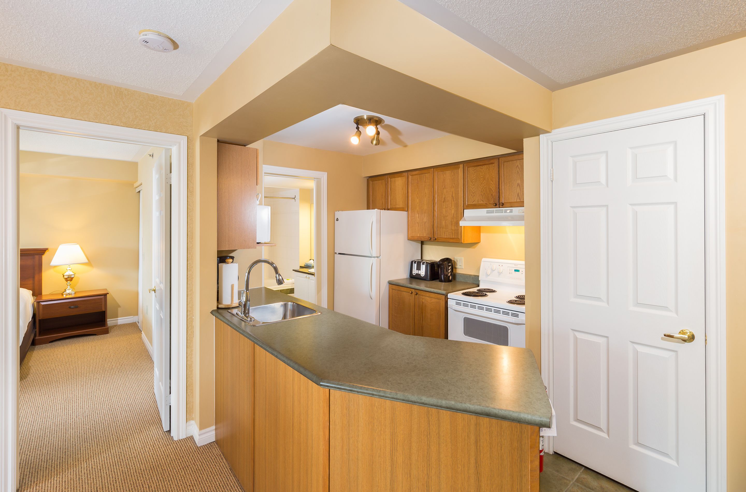 A compact kitchen with wooden cabinets, a built-in sink, and a refrigerator.